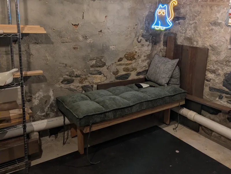 Finished daybed with a green tufted cushion and gray pillows against a stone wall